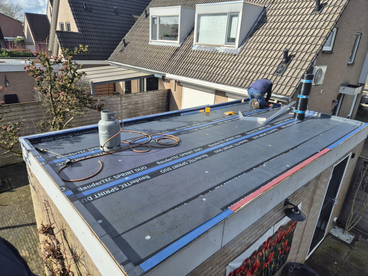Dakdekker brandt een nieuwe bitumen toplaag op een plat dak